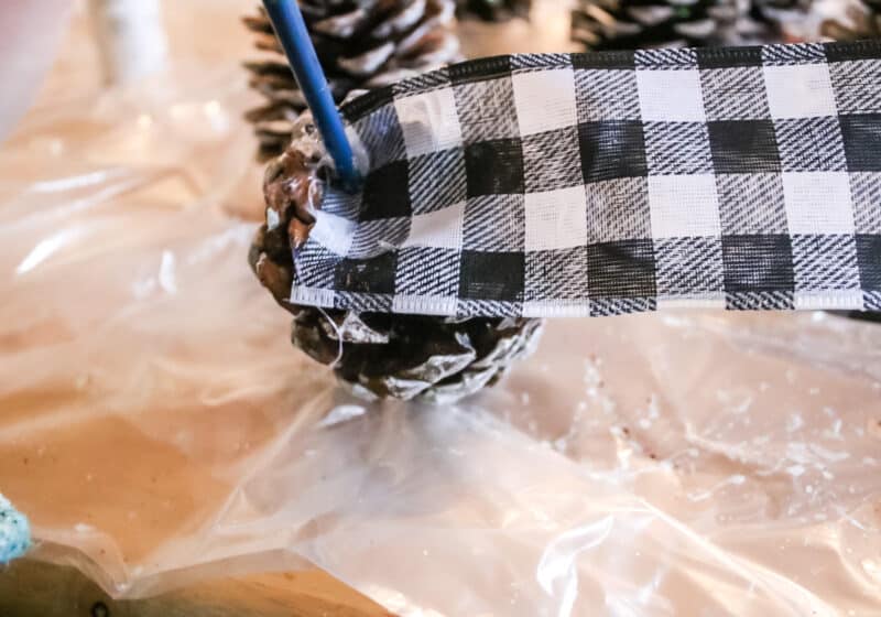 gluing the pine cones to ribbon