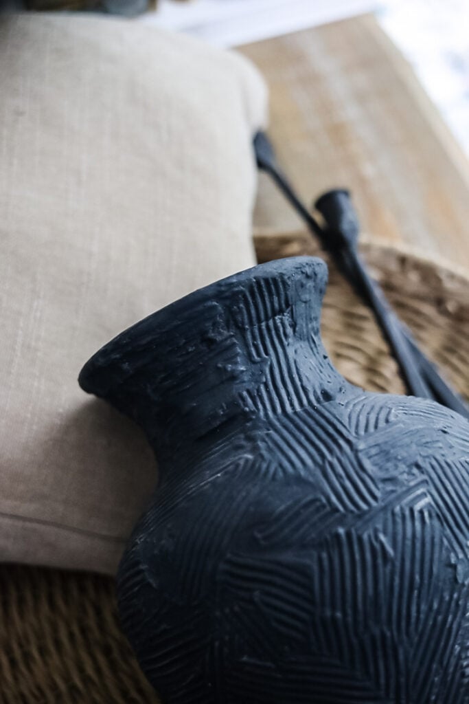 blue vase,beige pillow, black candlesticks, rattan tray