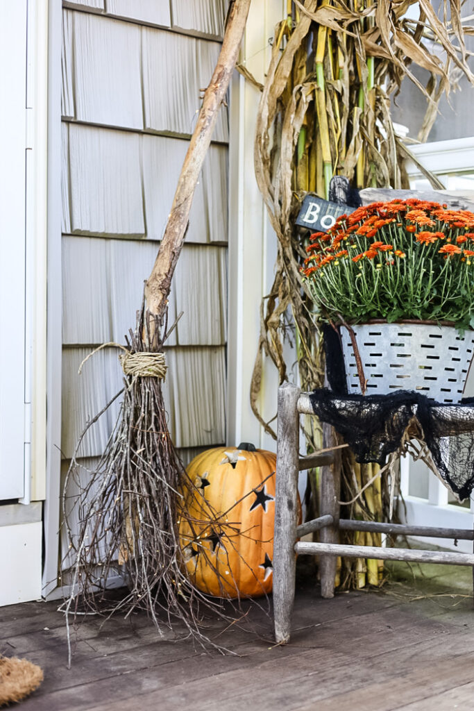 fall porch display with witch broom and pumpkin.