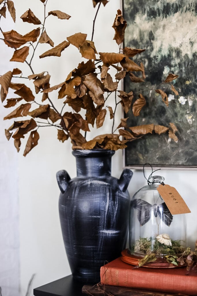 a tall black vase with dried branches