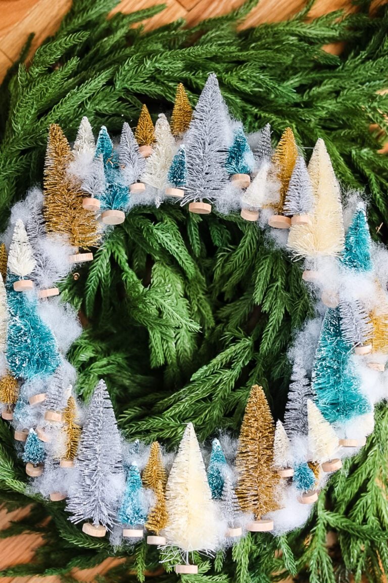 bottle brush tree wreath on top of green garland