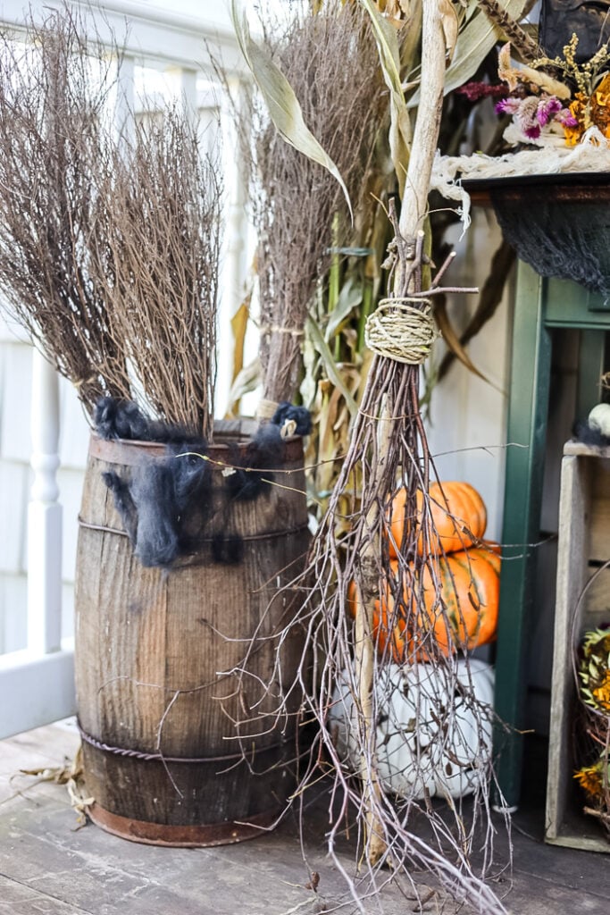 porch display with witch brooms and pumpkins.