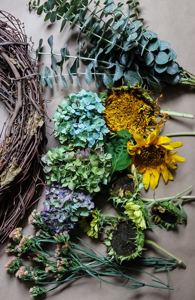 wreath making supplies including a grapevine wreath and a variety of flowers including eucalyptus, sunflowers, hydrangeas, and statice.