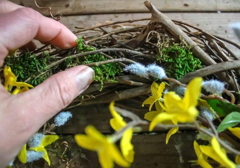 hand adding moss to a wreath