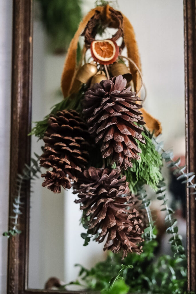 a pinecone door hanger hanging on the glass of a mirror