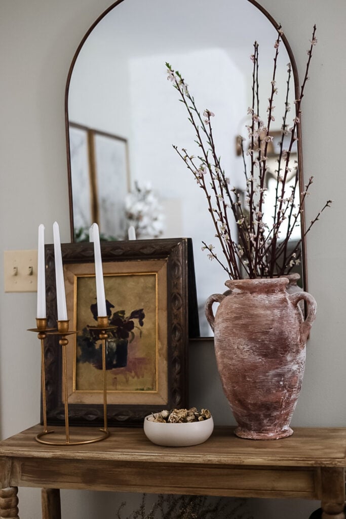 entryway table with large vase, cherry blossom branches, and painting